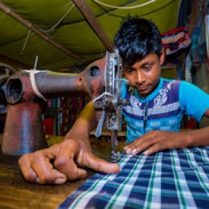 Bangladesh – October 28, 2019: A young boy working as a tailor labor at rural village tailor shop, Chandpur, Bangladesh.
